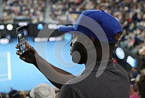 Unidentified spectator uses his cell phone to take images during tennis match at 2019 Australian Open in Melbourne Park