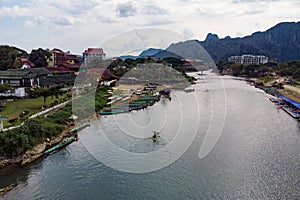Unidentified tourists are rowing kayak boats in Song River in Vang Vieng, top view, aerial view