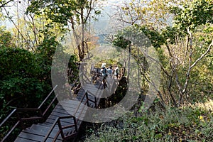 Unidentified tourists travel on wooden bridge.