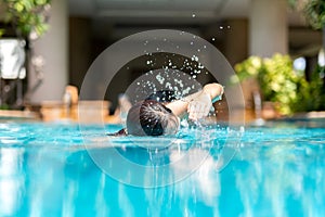 Unidentified woman doing front crawl swimming in swimming pool on vacation.