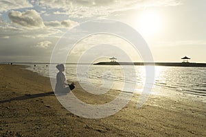 Unidentified woman exercising yoga on the beach