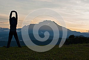 Unidentified woman stretching at the outdoor with Mount kinabalu as background
