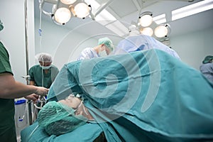 An unidentified woman are undergoing cesarean delivery by a medical team