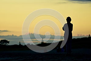 An unidentified young woman enjoying spectacular sunrise on the beach.