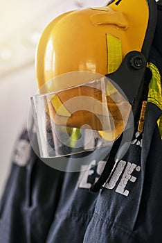 Uniform, helmet and clothes of firefighter on wall for rescue, emergency service and protection. Fire brigade, safety