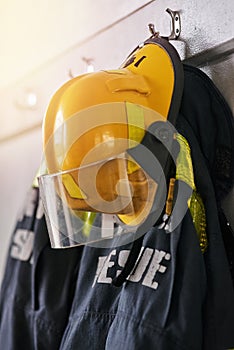 Uniform, helmet and jacket of firefighter on wall for rescue, emergency service and protection. Fire brigade, safety