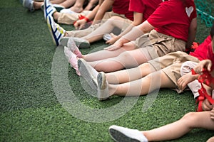 Uniformed children aligned legs sitting on grass