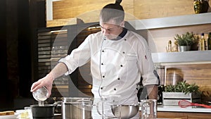 Uniformed cook prepares food in restaurant`s kitchen.