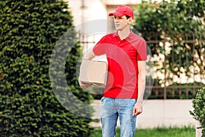 A uniformed courier holds a paper box. Delivery service