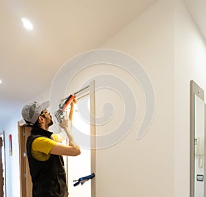 uniformed handyman with work clothes and goggles mounts in a wall hole a door slats. applying silicone and with clamps