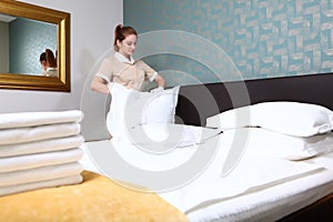 A uniformed maid changes the bed linen. Room cleaning in an expensive hotel. Hands in white cotton gloves. The concept of the