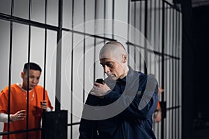 A uniformed overseer in an asian prison makes an evening tour of the cells with prisoners