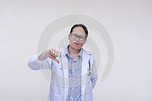 An unimpressed and dismissive doctor gives the thumbs down sign. Of asian descent, middle aged male in his 40s.