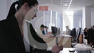 Uninteresting work, depressed attractive girl in eyeglasses looks at himself sitting at table