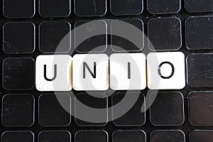 Unio text word crossword. Alphabet letter blocks game texture background. White alphabetical letters on black background photo