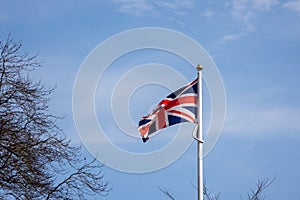 Union Jack flag against blue sky with clouds