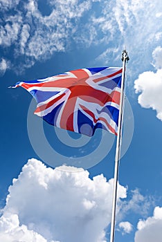 Union Jack Flag - UK Flag Blowing in the Wind on Blue Sky with Clouds