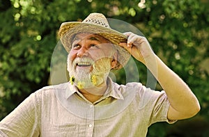 Union with nature. senior man with gray beard in straw hat. happy retirement. grandfather smiling while watching pink