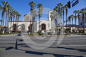 Union Station train station surrounded by office buildings, parked cars, tall lush green palm trees and plants and people walking