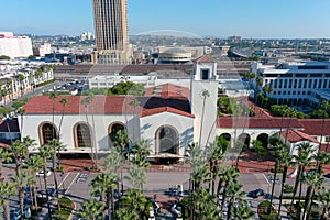 Union Station train station surrounded by office buildings, parked cars, tall lush green palm trees and plants and people walking