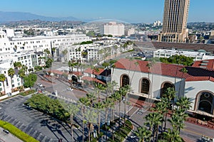 Union Station train station surrounded by office buildings, parked cars, tall lush green palm trees and plants and people walking