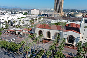 Union Station train station surrounded by office buildings, parked cars, tall lush green palm trees and plants and people walking