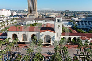 Union Station train station surrounded by office buildings, parked cars, tall lush green palm trees and plants and people walking