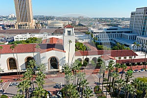 Union Station train station surrounded by office buildings, parked cars, tall lush green palm trees and plants and people walking