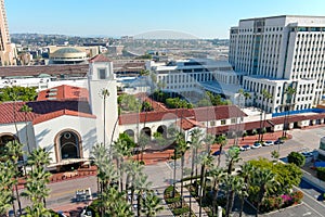 Union Station train station surrounded by office buildings, parked cars, tall lush green palm trees and plants and people walking