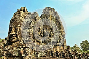 The unique Bayon temple. Against the blue sky towers with gigantic faces carved from stone rise