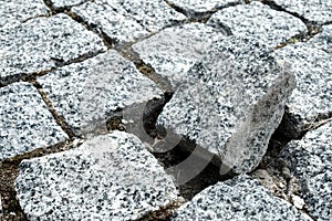 Unique broken stone of the cobblestone street in an old medieval city. Outsider of a community. Damaged, alone and different.