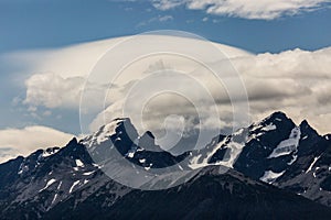 Unique Cloud Formation Over Rugged Snowy Mountain Range