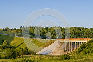 Unique concrete bridge and road against background of forest