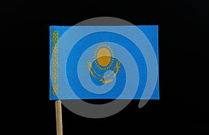 A unique flag of Kazakhstan on toothpick on black background. A gold sun with 32 rays above a soaring golden steppe eagle, both