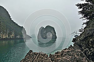 Unique Halong Bay, Vietnam. Over calm emerald water rise islands with steep slopes