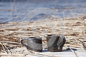 Unique handmade two cups with folk sign with blurred lake on background