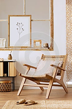 Unique living room interior with stylish rattan armchair, design furniture, dried flowers, mock up poster frames, wooden floor.