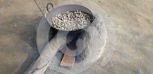 A unique method of roasting peanuts on an earthen stove in India