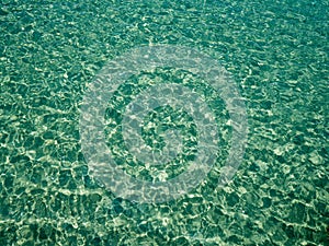 Unique perspective green crystal sea water surface ripple with sun reflection. Water background. Ocean water texture