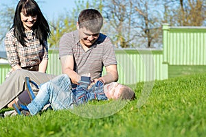 Unique perspective of two loving parents lying on the grass with their baby