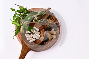 Unique photography of Cinnamon, dry ginger, black cardamom, mace arils, long pepper, and herbal capsules in wooden spoon with