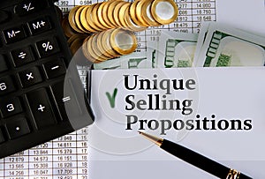 UNIQUE SELLING PROPOSITIONS - words on a white sheet on the background of a calculator, coins and dollar bills