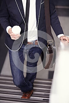 Unique sense of style. Cropped image of a trendy young man walking up the stairs with coffee.