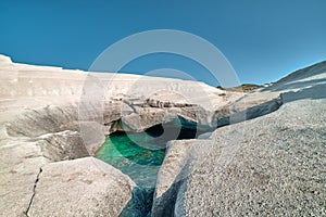 Unique white rocks and emerald green water in sea cave, Sarakiniko beach, Milos island, Greece. Empty cliffs, summer