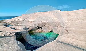 Unique white rocks and emerald green water in sea cave, Sarakiniko beach, Milos island, Greece. Empty cliffs, summer