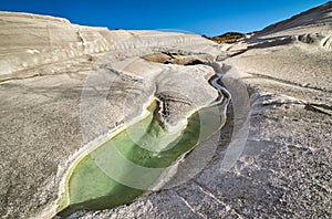 Unique white rocks on Sarakiniko beach and natural trapped water pool, Milos island, Greece. Empty cliffs, summer