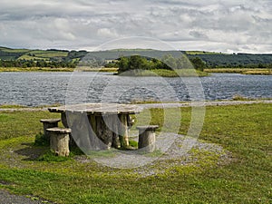 Unique wooden table and bench in a park by a lake, Cloudy sky