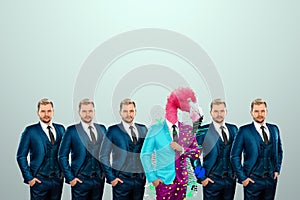 Uniqueness creative background, among the crowd of businessmen multicolored freak flamingo. Competitive advantage, standing out