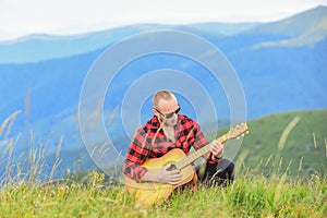 In unison with nature. Musician hiker find inspiration in mountains. Keep calm and play guitar. Man with guitar on top