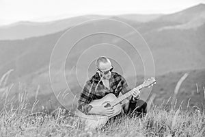 In unison with nature. Musician hiker find inspiration in mountains. Keep calm and play guitar. Man with guitar on top